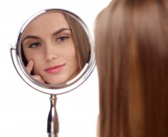 鏡で自分の肌をチェックしている女性