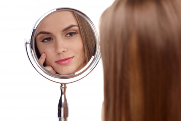 鏡で自分の肌をチェックしている女性