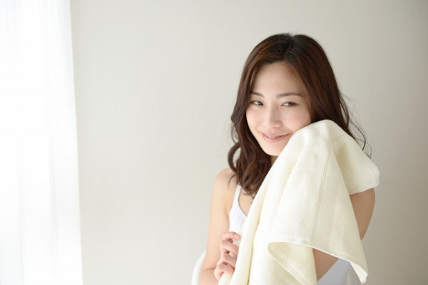 タオルを顔にあてている女性